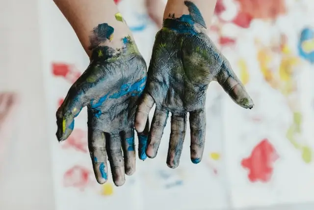 Child painting at table with art supplies, focused on creativity and self-expression