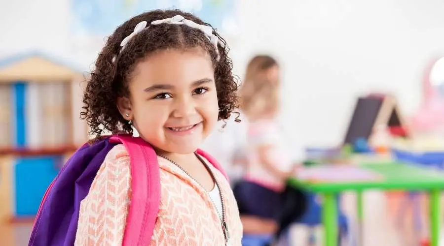 Smiling child with backpack in a classroom, ready for the day