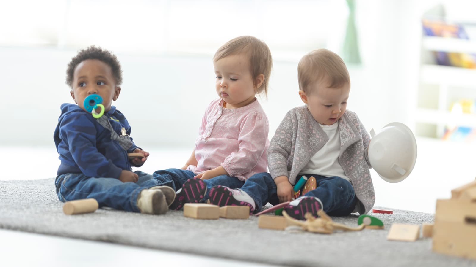 Three small children playing quietly on the floor