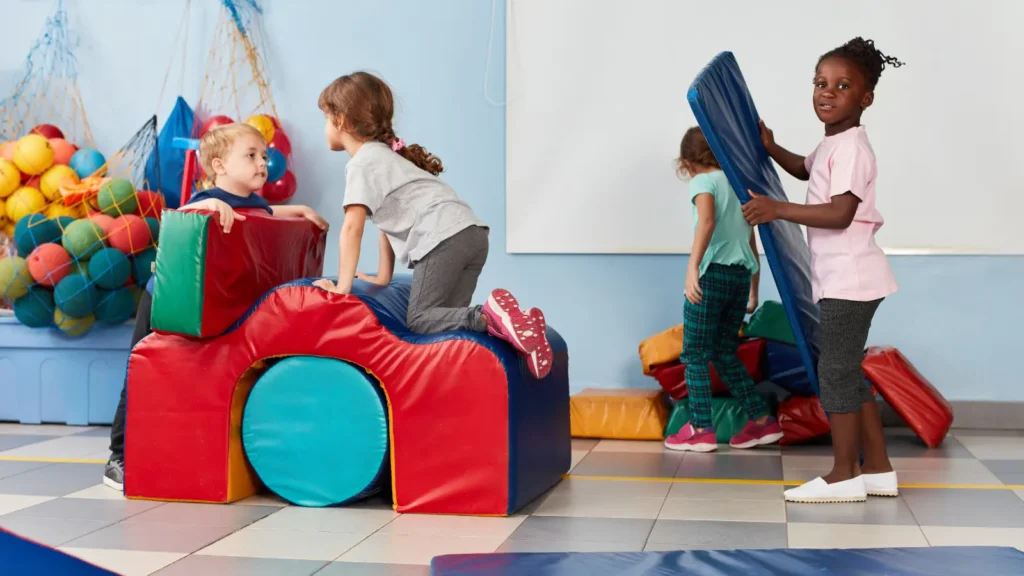 Kids building and climbing on padded play equipment indoors