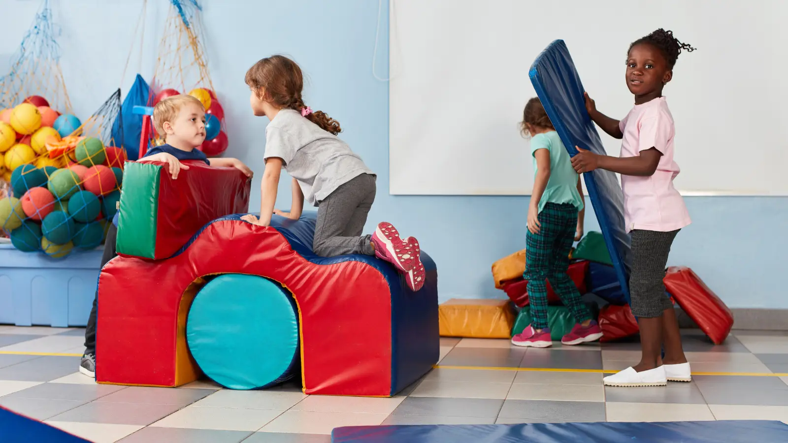 Kids building and climbing on padded play equipment indoors