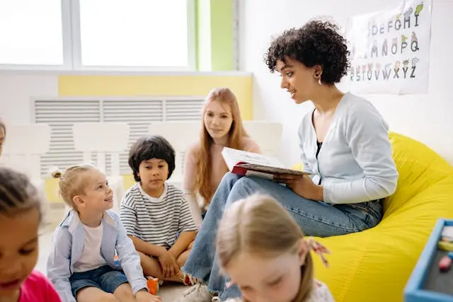 Adult reads to children seated together in a bright classroom during story time